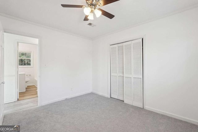 unfurnished bedroom with carpet, visible vents, baseboards, a closet, and crown molding