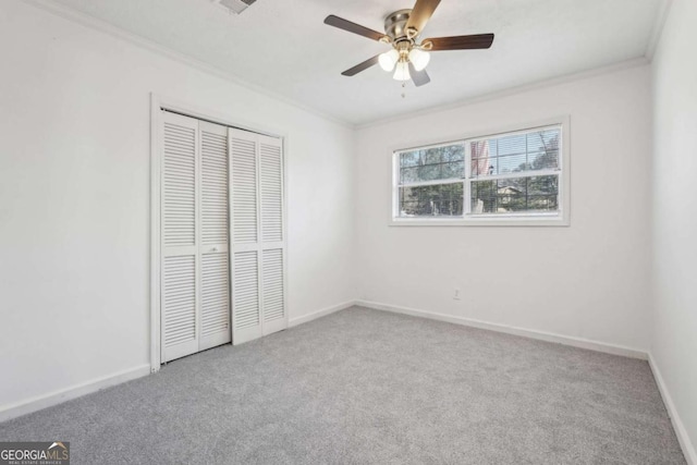 unfurnished bedroom with carpet, baseboards, ceiling fan, a closet, and crown molding