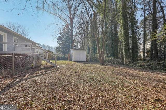 view of yard featuring an outbuilding, stairway, a storage unit, and fence