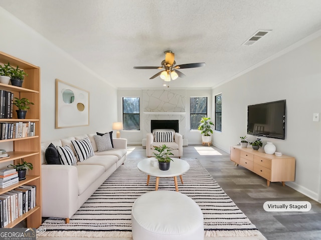 living room with visible vents, wood finished floors, a fireplace, and crown molding