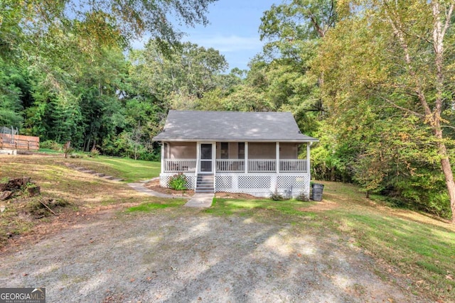 view of front of house with a porch, a forest view, and a front yard