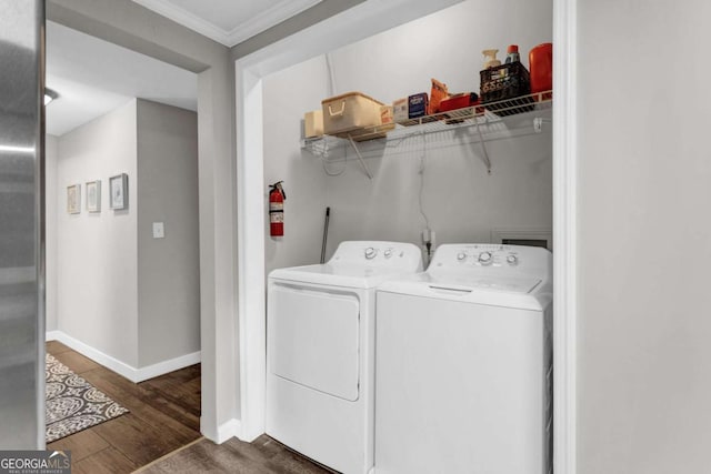 laundry area featuring wood finished floors, baseboards, laundry area, washer and dryer, and crown molding