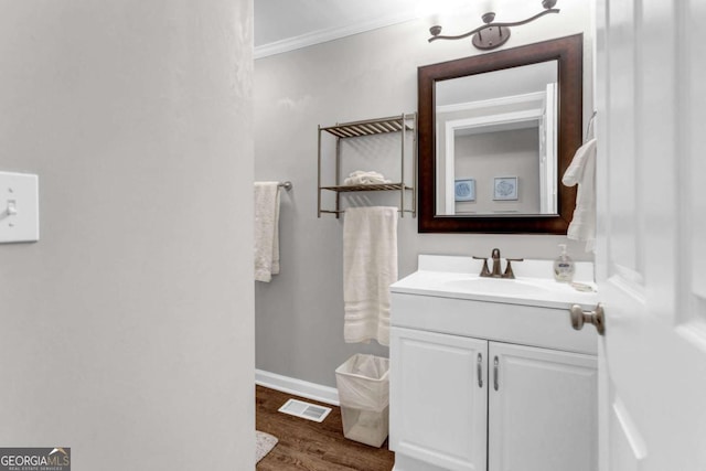 bathroom with vanity, wood finished floors, baseboards, visible vents, and ornamental molding