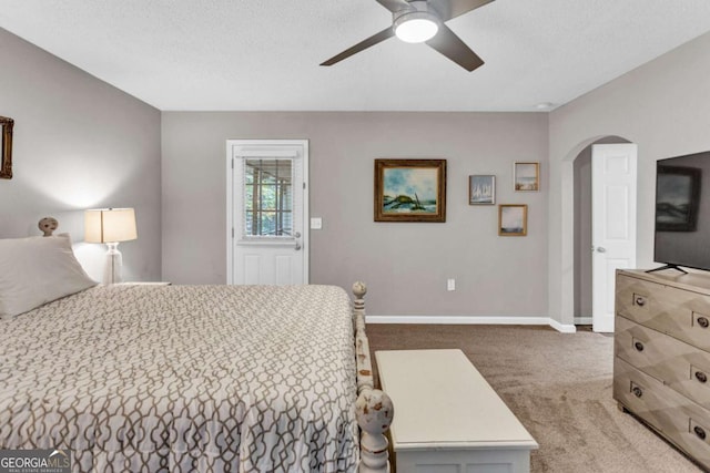 carpeted bedroom featuring ceiling fan, baseboards, arched walkways, and a textured ceiling