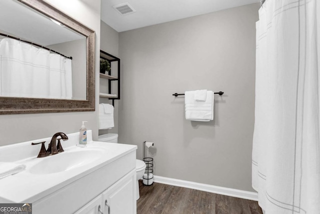 bathroom with visible vents, toilet, wood finished floors, baseboards, and vanity