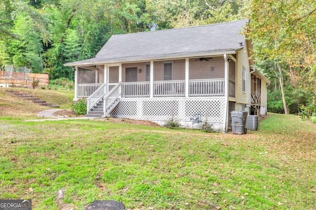 view of front of house with a front yard, a view of trees, and a sunroom