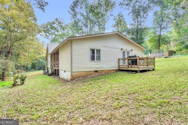 rear view of property with crawl space, a lawn, and a wooden deck