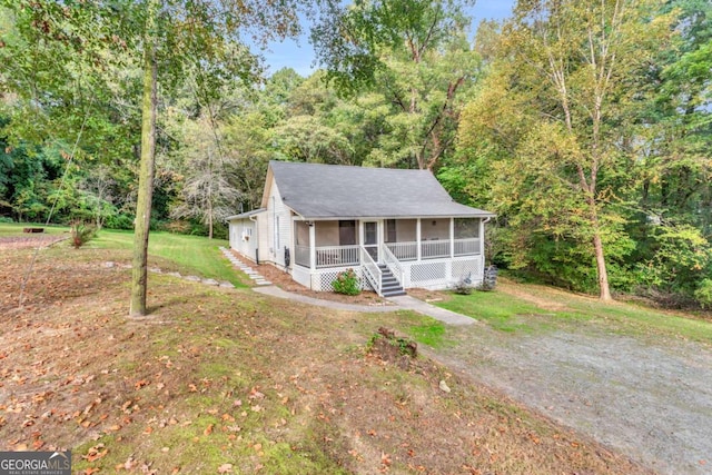 view of front facade with a front yard, a porch, a wooded view, and driveway