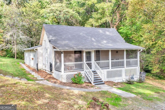 view of front of home featuring a forest view, a front lawn, and a sunroom