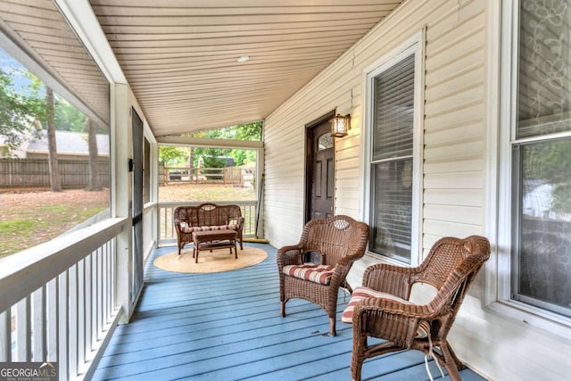 wooden terrace featuring a porch and fence