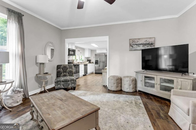 living room with dark wood finished floors, a ceiling fan, crown molding, and baseboards