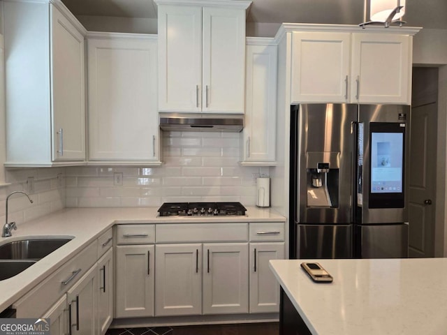 kitchen with under cabinet range hood, white cabinetry, appliances with stainless steel finishes, and a sink