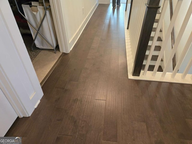 corridor featuring dark wood finished floors, stairway, and baseboards