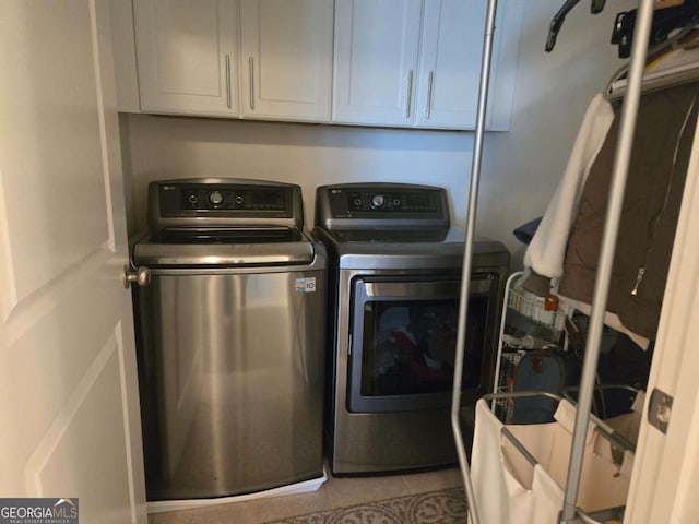 laundry area with washing machine and clothes dryer, tile patterned flooring, and cabinet space