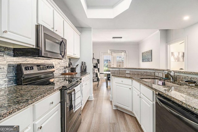 kitchen with a sink, stainless steel appliances, white cabinets, and light wood finished floors