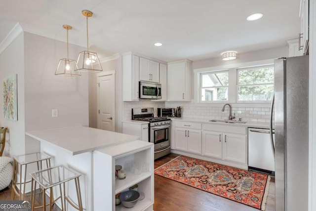 kitchen featuring a sink, backsplash, white cabinetry, stainless steel appliances, and a peninsula