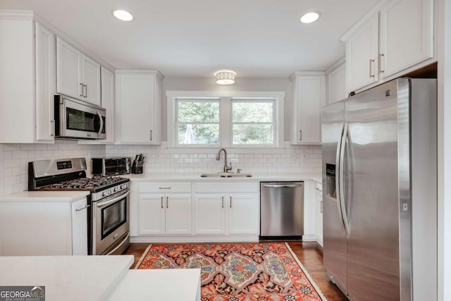 kitchen with white cabinetry, decorative backsplash, appliances with stainless steel finishes, and a sink