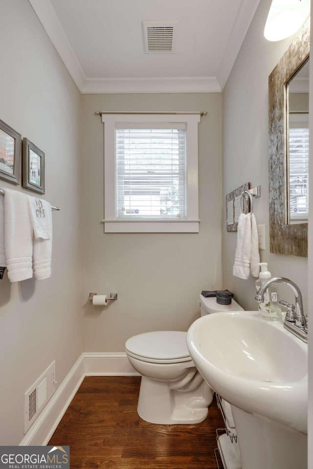 half bathroom with wood finished floors, visible vents, and ornamental molding