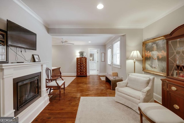 living room with a fireplace with raised hearth, dark wood finished floors, recessed lighting, crown molding, and baseboards