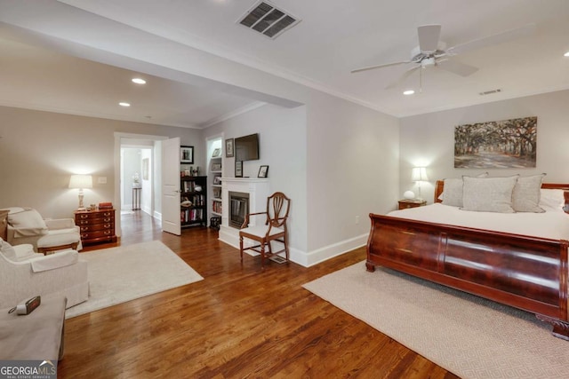 bedroom with visible vents, baseboards, recessed lighting, wood finished floors, and a glass covered fireplace