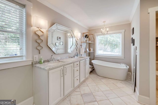 bathroom with a freestanding tub, ornamental molding, a sink, an inviting chandelier, and double vanity