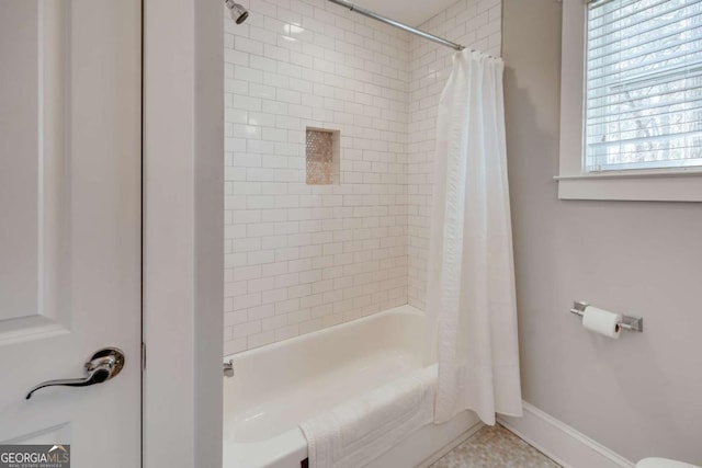 bathroom featuring baseboards and shower / tub combo with curtain