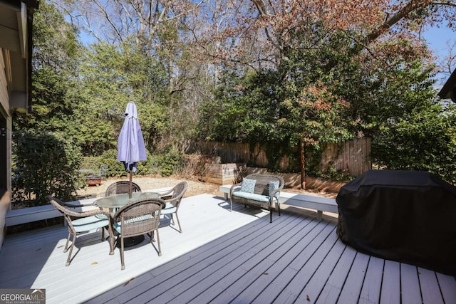 wooden deck featuring outdoor dining space, area for grilling, and fence