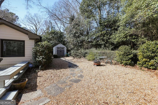 view of yard featuring a shed, a fire pit, and an outdoor structure