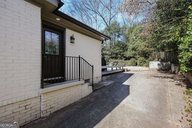 view of home's exterior with a patio area, fence, and brick siding