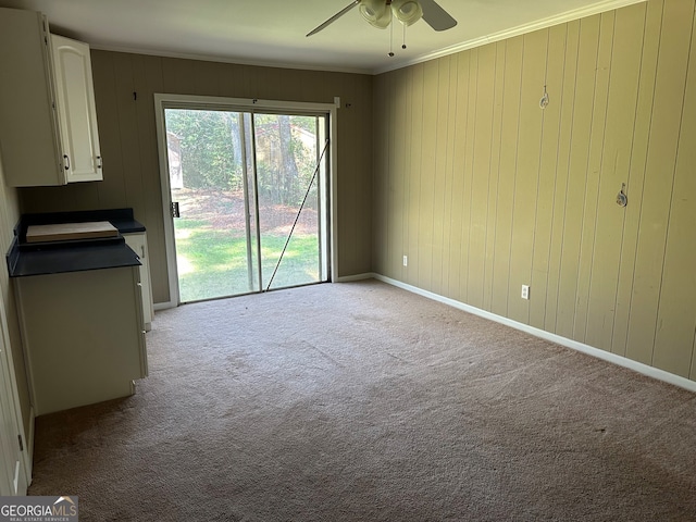 unfurnished living room featuring ceiling fan, light colored carpet, baseboards, and ornamental molding