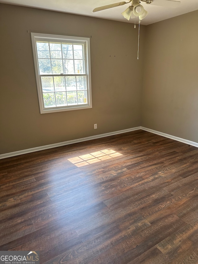 spare room featuring ceiling fan, baseboards, and dark wood-style flooring