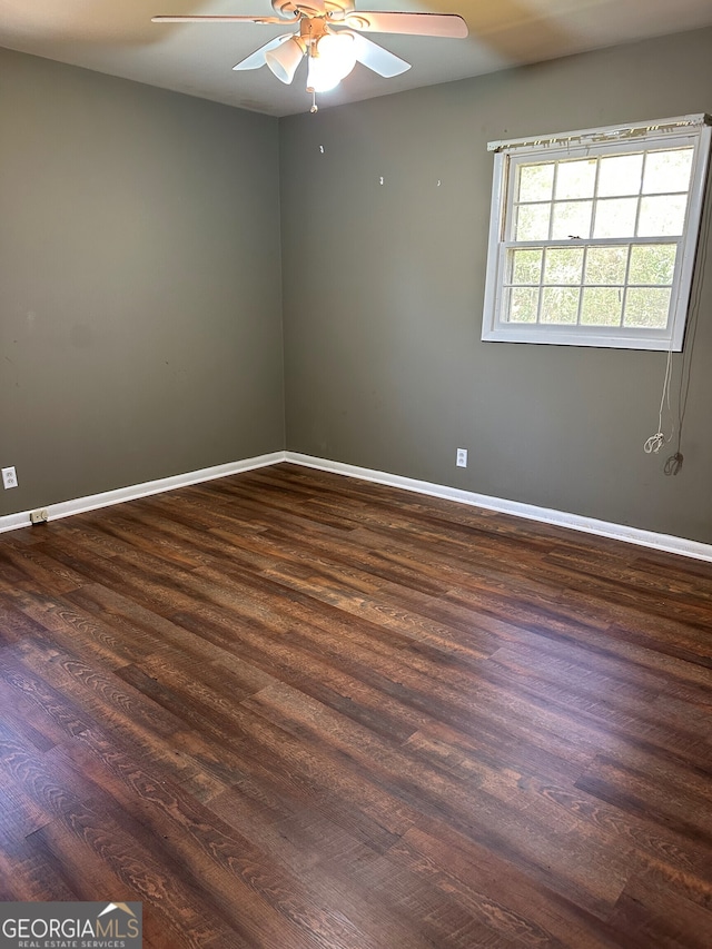 unfurnished room with dark wood-style floors, a ceiling fan, and baseboards