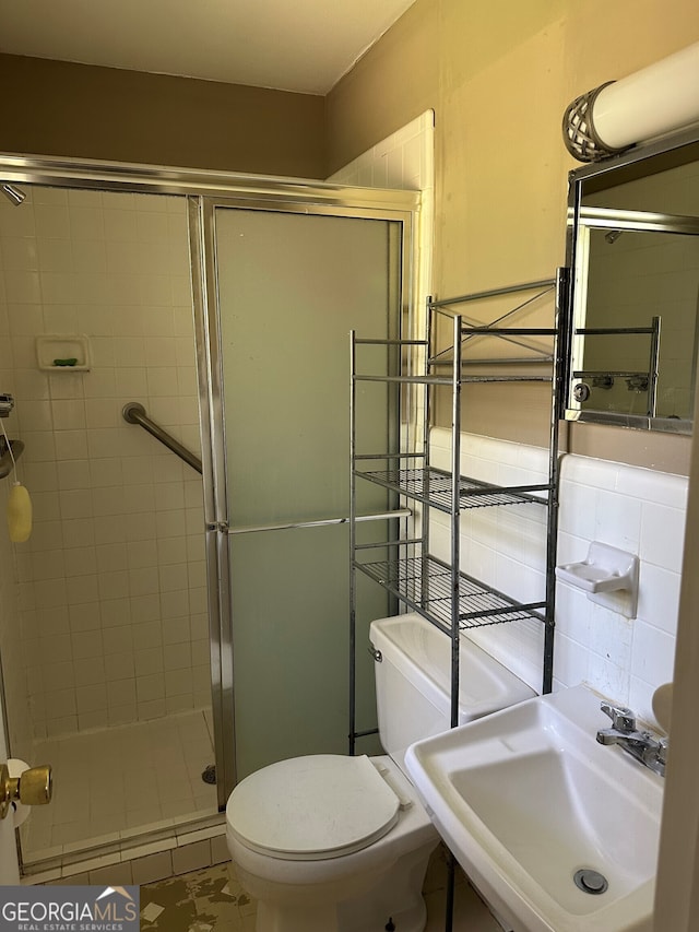 full bathroom with a stall shower, toilet, and a sink