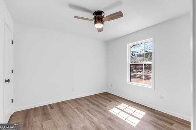 spare room featuring wood finished floors, baseboards, and ceiling fan