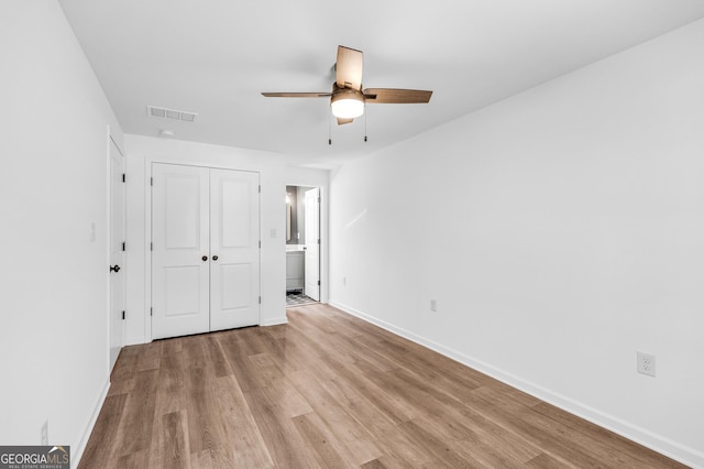 unfurnished bedroom with visible vents, a closet, connected bathroom, light wood-style floors, and baseboards