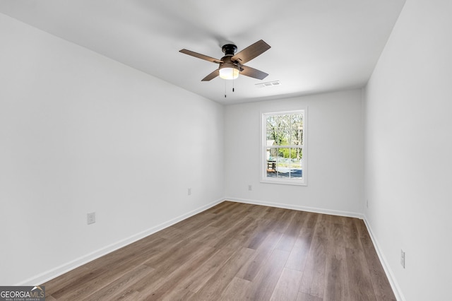 spare room with visible vents, baseboards, a ceiling fan, and wood finished floors