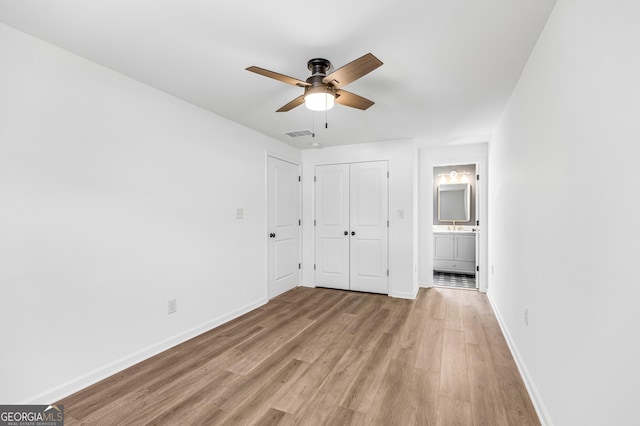 unfurnished bedroom with visible vents, connected bathroom, light wood-style floors, baseboards, and ceiling fan