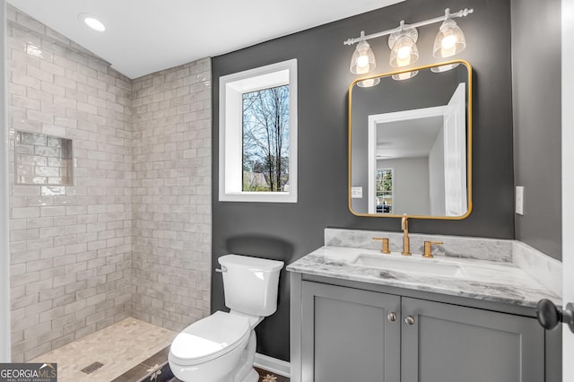 bathroom featuring vanity, toilet, and a tile shower