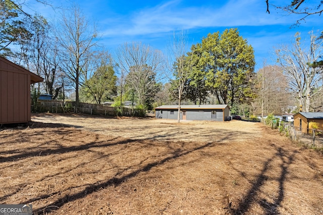 view of yard featuring an outdoor structure, fence, and a detached garage