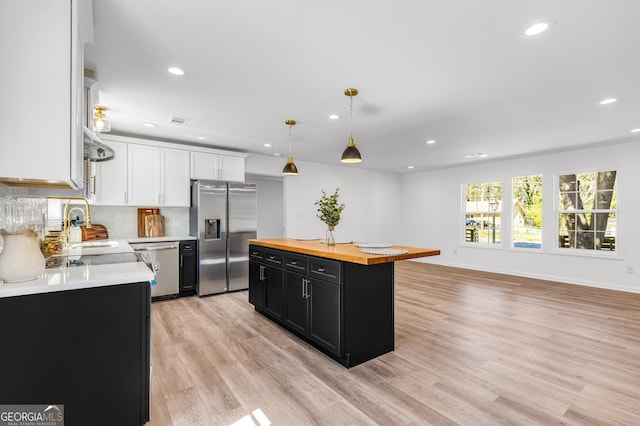 kitchen featuring dark cabinets, butcher block countertops, stainless steel appliances, white cabinetry, and light wood-type flooring