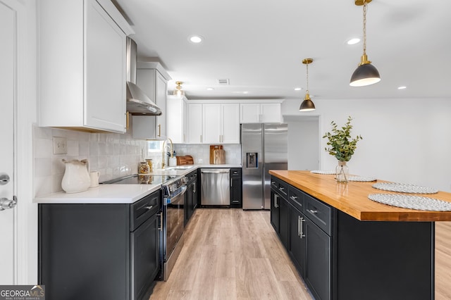 kitchen featuring butcher block counters, appliances with stainless steel finishes, light wood-style floors, white cabinetry, and a sink