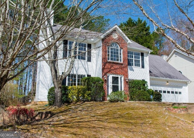 colonial inspired home featuring a front yard, an attached garage, and brick siding