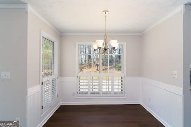 unfurnished dining area featuring a textured ceiling, a wainscoted wall, dark wood-type flooring, and a notable chandelier