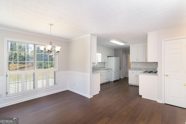 kitchen featuring white appliances, a wainscoted wall, an inviting chandelier, dark wood-style flooring, and white cabinets