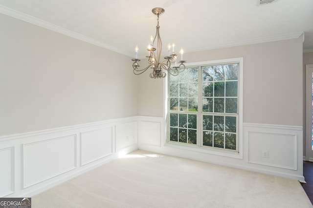 unfurnished dining area featuring carpet flooring, an inviting chandelier, wainscoting, and crown molding