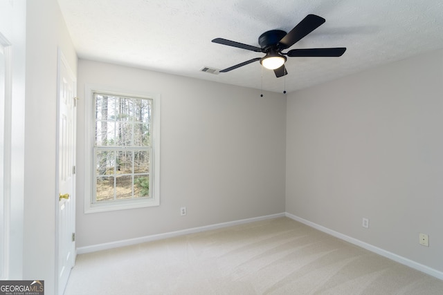 unfurnished room with baseboards, light colored carpet, a ceiling fan, and a textured ceiling