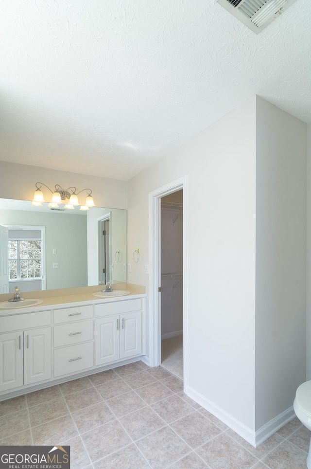 bathroom featuring a sink, visible vents, double vanity, and tile patterned floors