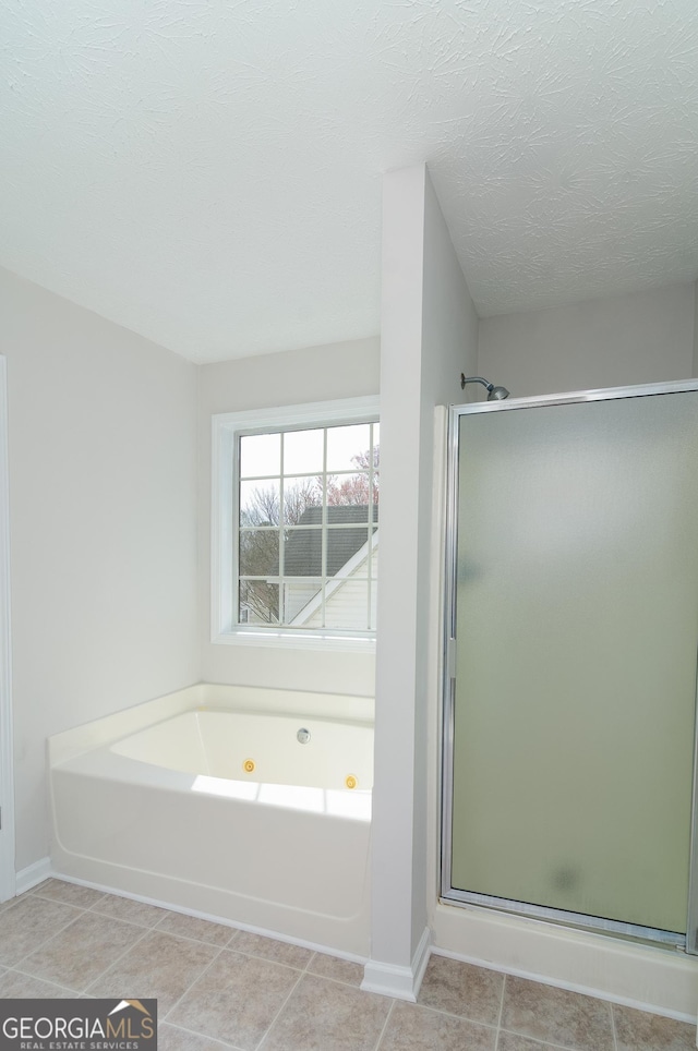 full bath with a jetted tub, baseboards, a stall shower, tile patterned floors, and a textured ceiling