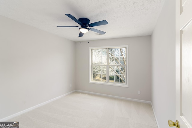 empty room featuring baseboards, light carpet, a textured ceiling, and ceiling fan