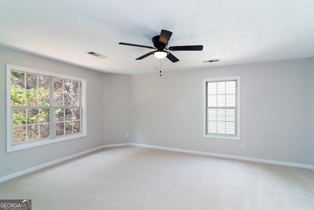 unfurnished room featuring light carpet, visible vents, a textured ceiling, and baseboards